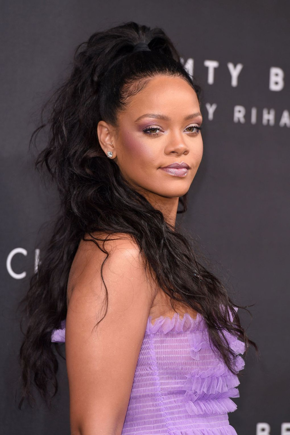 Rihanna pro uvedení své kolekce Fenty Beauty v Londýně zvolila fialové líčení ke světle fialovým šatům
