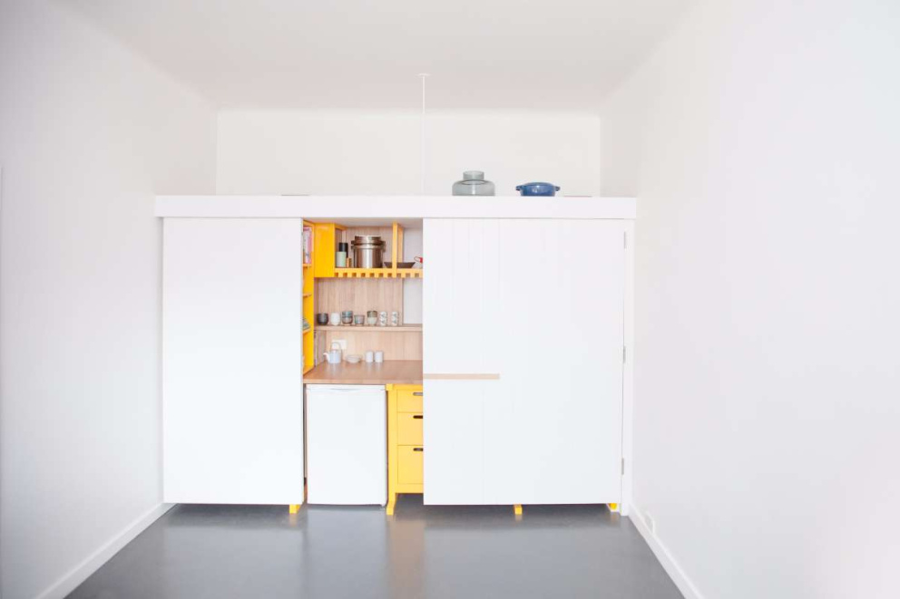 Kuchyně se dá otevřít do obou stran,&nbsp;vlevo jsou hluboké úložné boxy a knihovnička (ta je přístupná z prostoru za kuchyní, kde má majitel ložnici).
