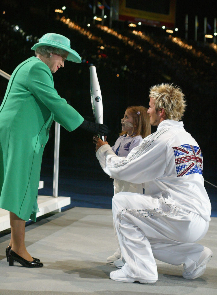 Fotbalista&nbsp;David Beckham&nbsp;se s královnou Alžbětou II. setkal na Manchester stadionu na zahájení Her Commonwealthu v roce 2002. Na sobě měl bílou teplákovou soupravu ozdobenou kamínky a britskou vlajkou.
