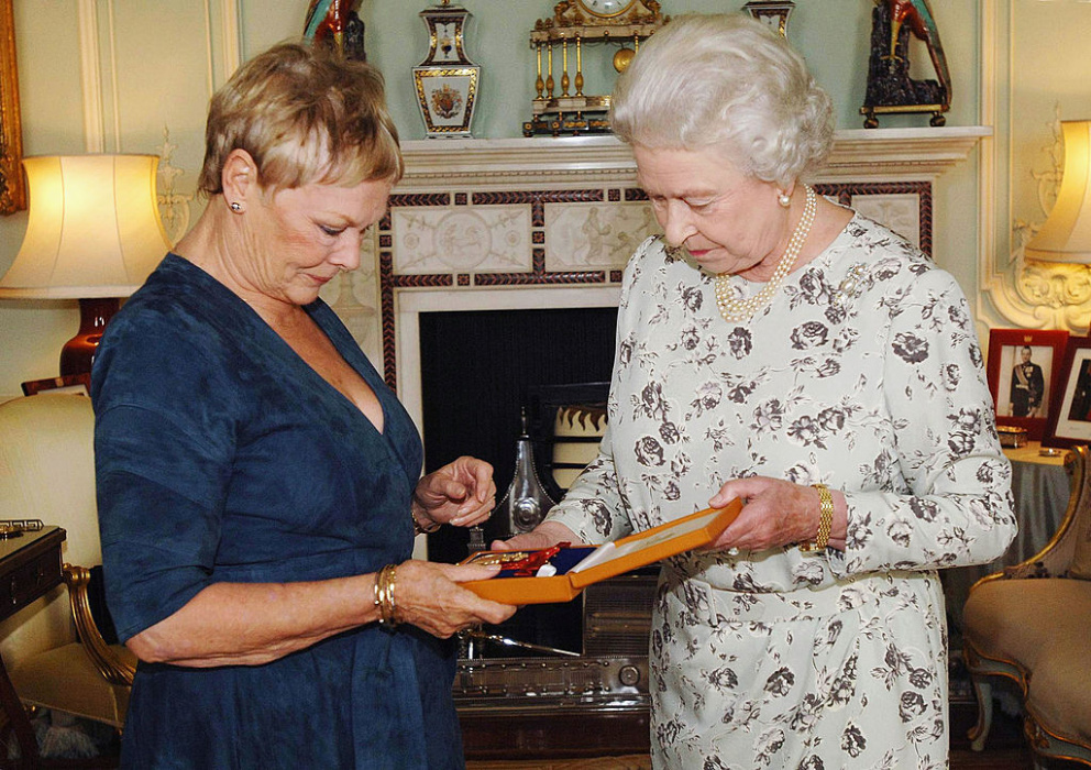 Herečka&nbsp;Judi Dench&nbsp;se s královnou Alžbětou II. setkala přímo v Buckhinghamském paláci v roce 2005. Na sobě měla jednoduché modré šaty.
