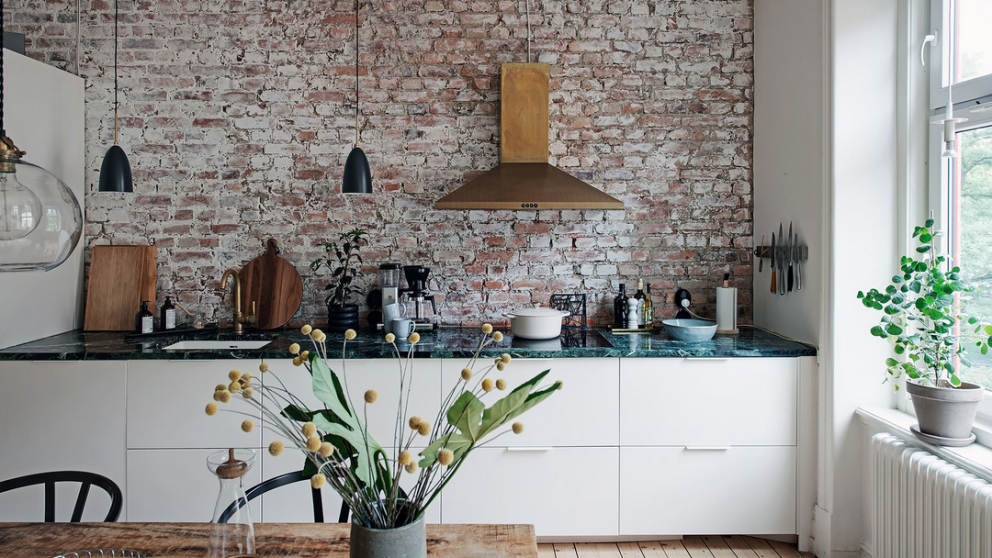 Odhalené cihly v kuchyni a veliká okna, to jsou dominantní prvky tohoto elegantního švédského bytu