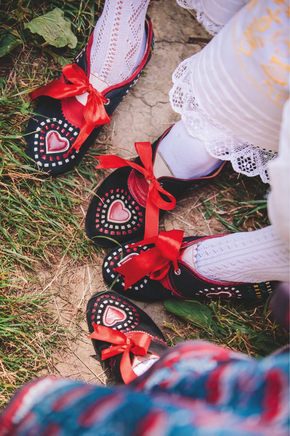 Vyšívané kožené sváteční boty zdobí červená stuha