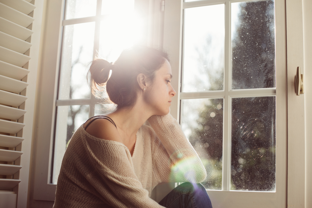 Smutná přemýšlející žena hledící z okna
