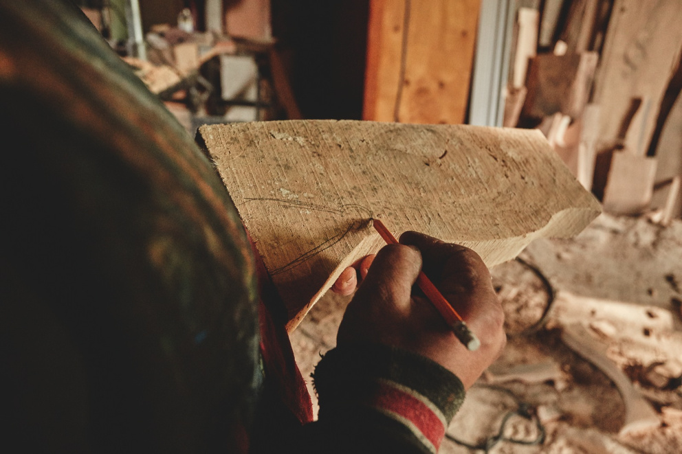 Základní tvar budoucí figurky si řezbář na dřevo předkresluje tužkou