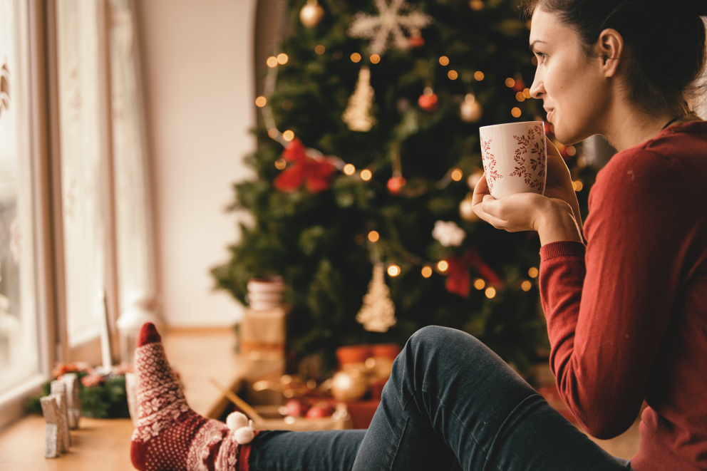 Žena pijící horký nápoj u vánočního stromku