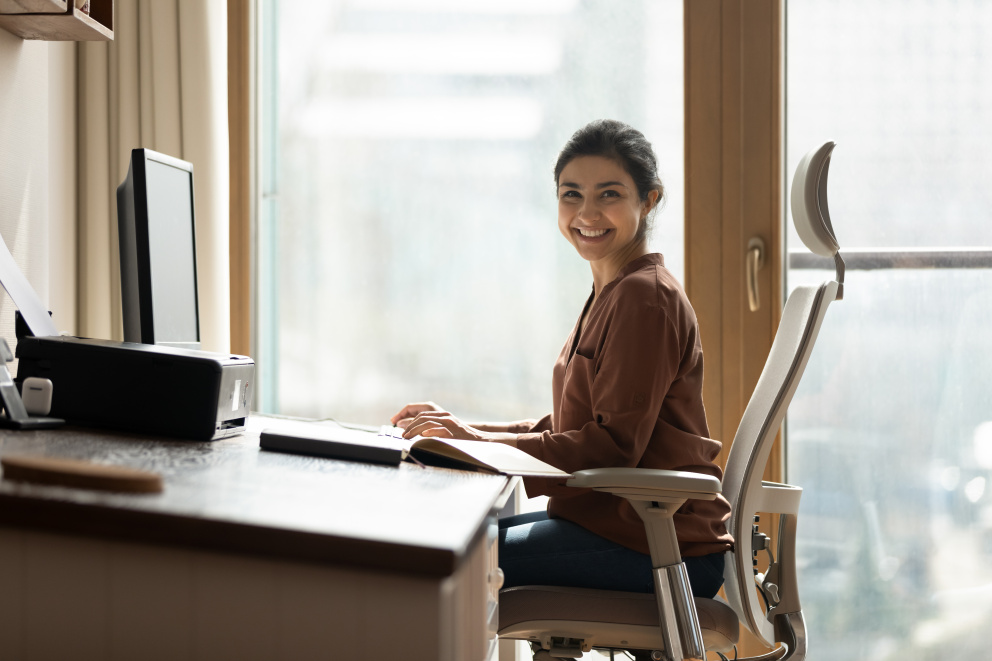 Žena sedící u počítače a smějící se