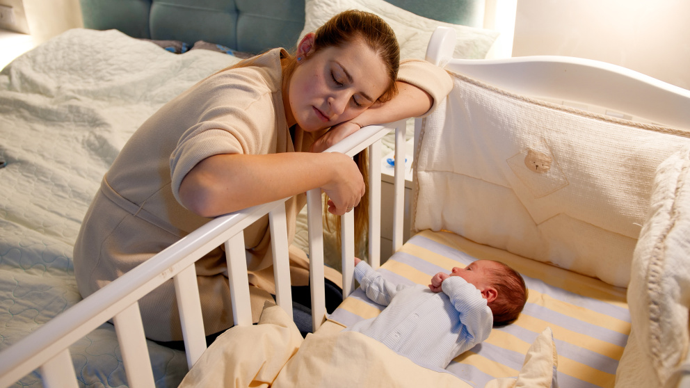 Unavená matky u postýlky novorozence
