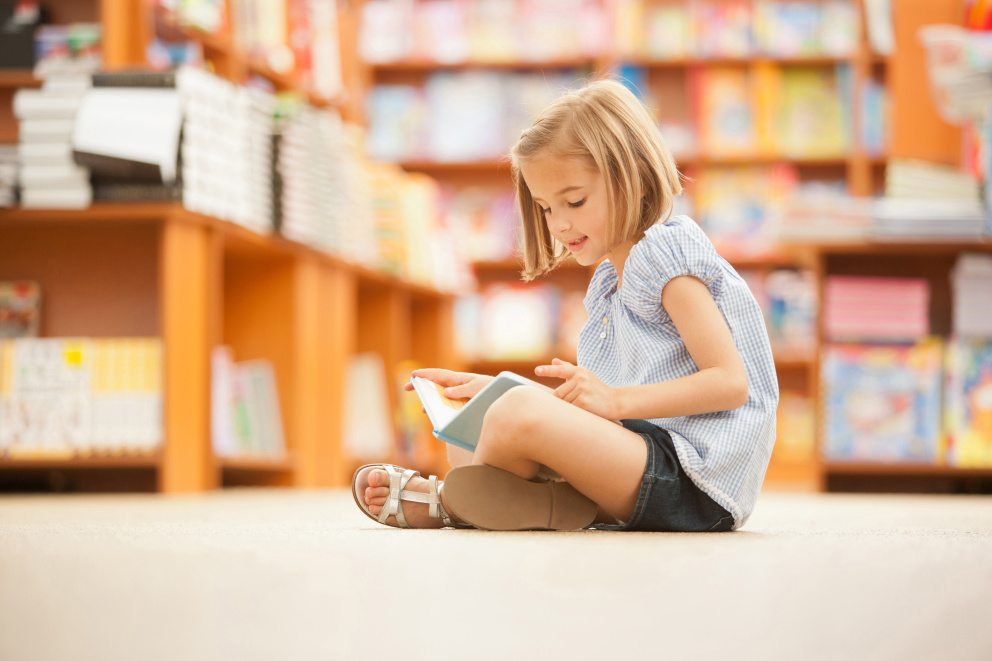 Dívka si čte knihu v knihovně